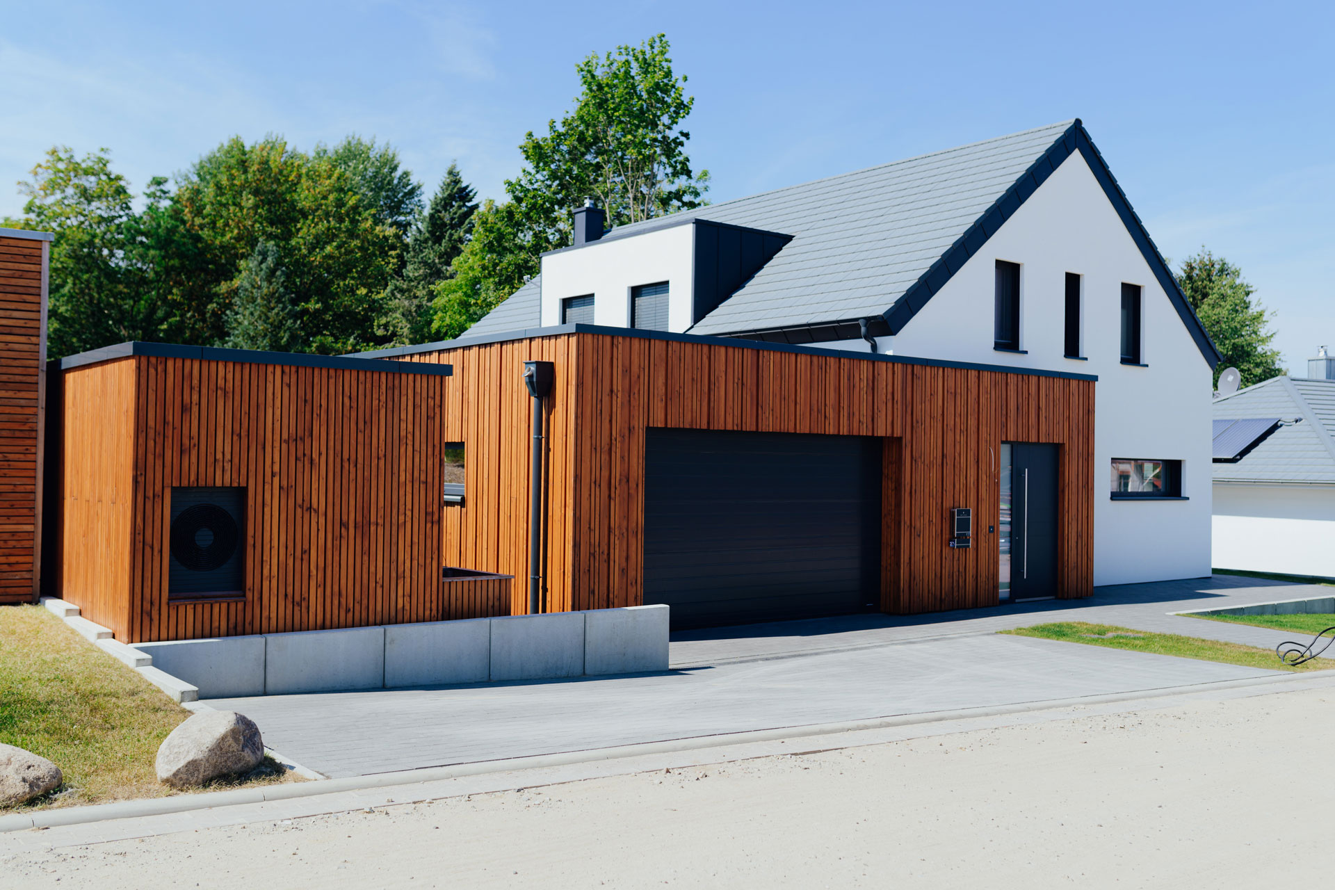 Ein Einfamilienhaus hat einen großzügigen Holzanbau.