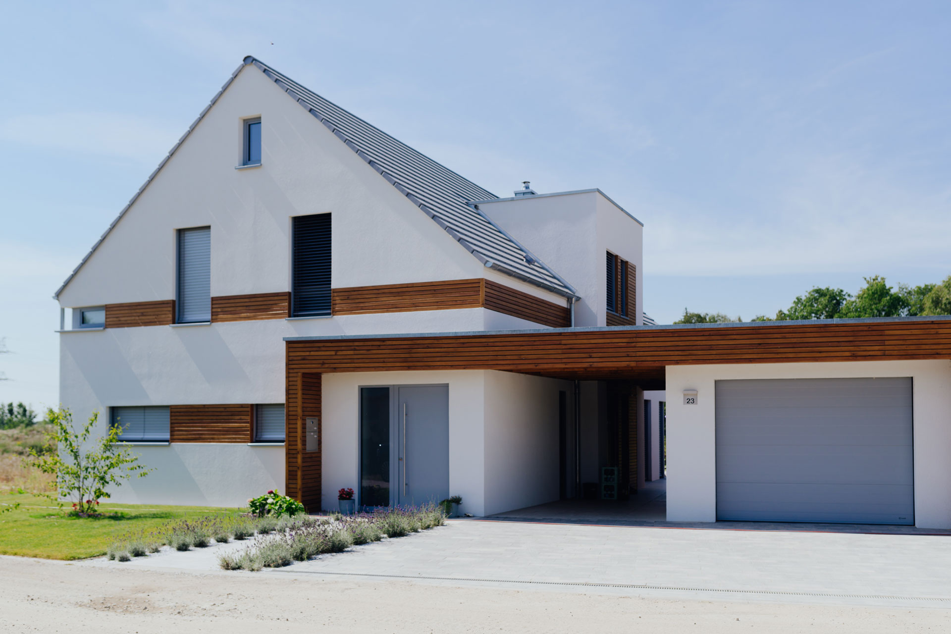 Neben dem Eingangsbereich ist der Garagenanbau. Eingang und Anbau verbindet eine Holzüberdachung