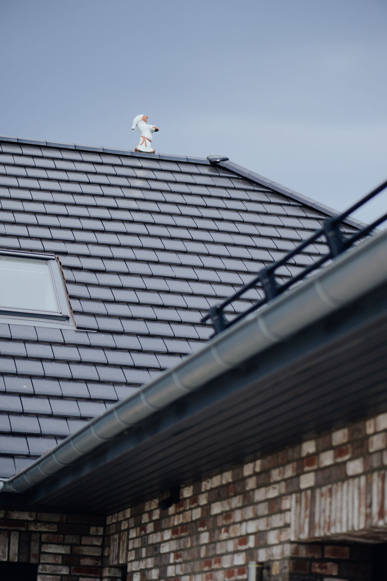 Auf dem Dachgiebel läuft eine dekorative Figur, die scheinbar schlafwandelt.
