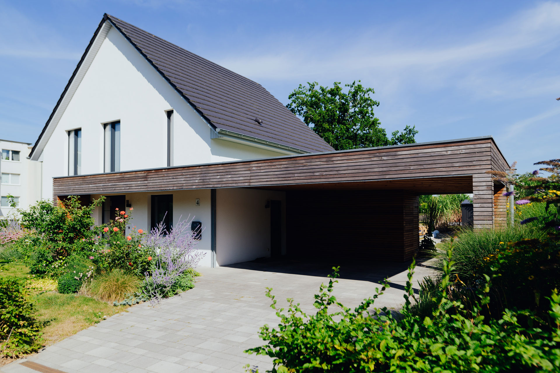 Ein Einfamilienhaus hat als seitlichen Anbau einen großzügigen Carport.