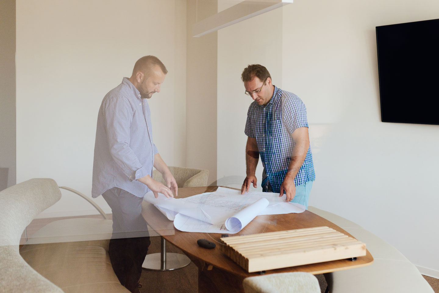 Marco Krenz und Stefan Müller stehen an einem Tisch. Dort liegen Baupläne.