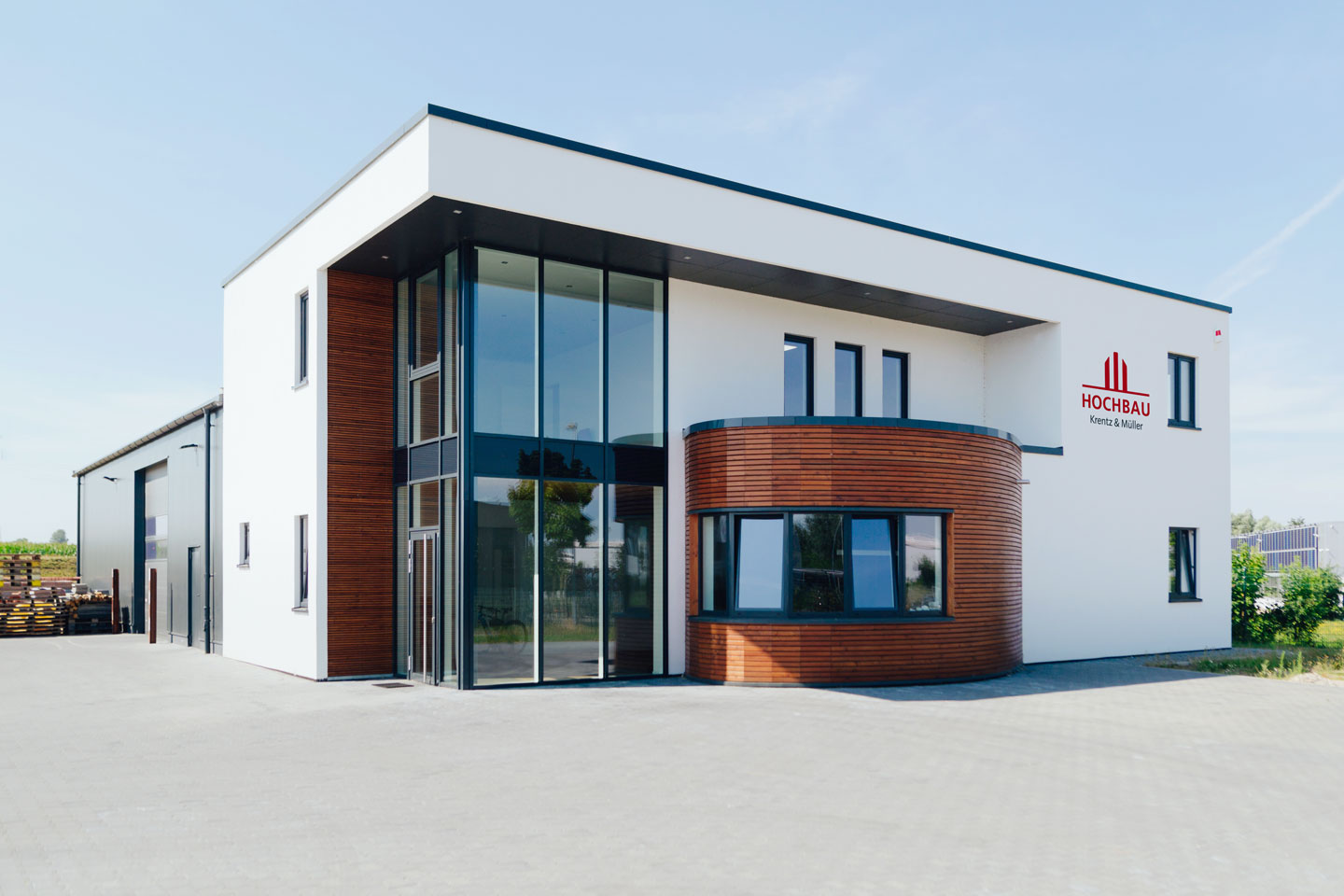 Das große eckige Firmengebäude hat einen halbrunden Holzvorbau.