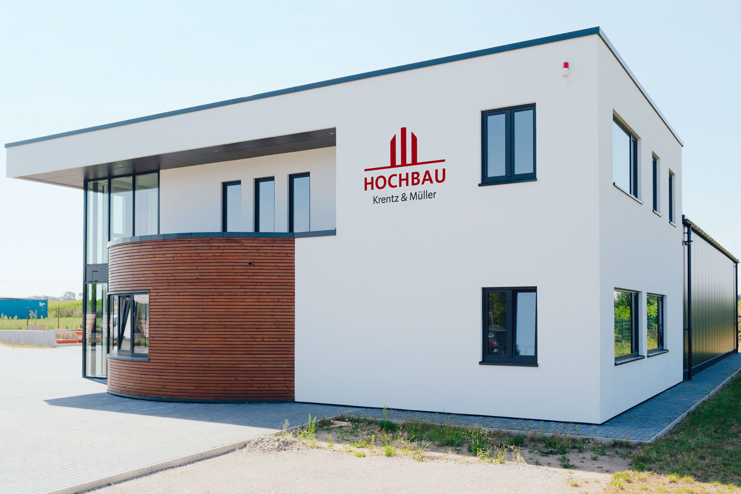 Das große eckige Firmengebäude hat einen halbrunden Holzvorbau.