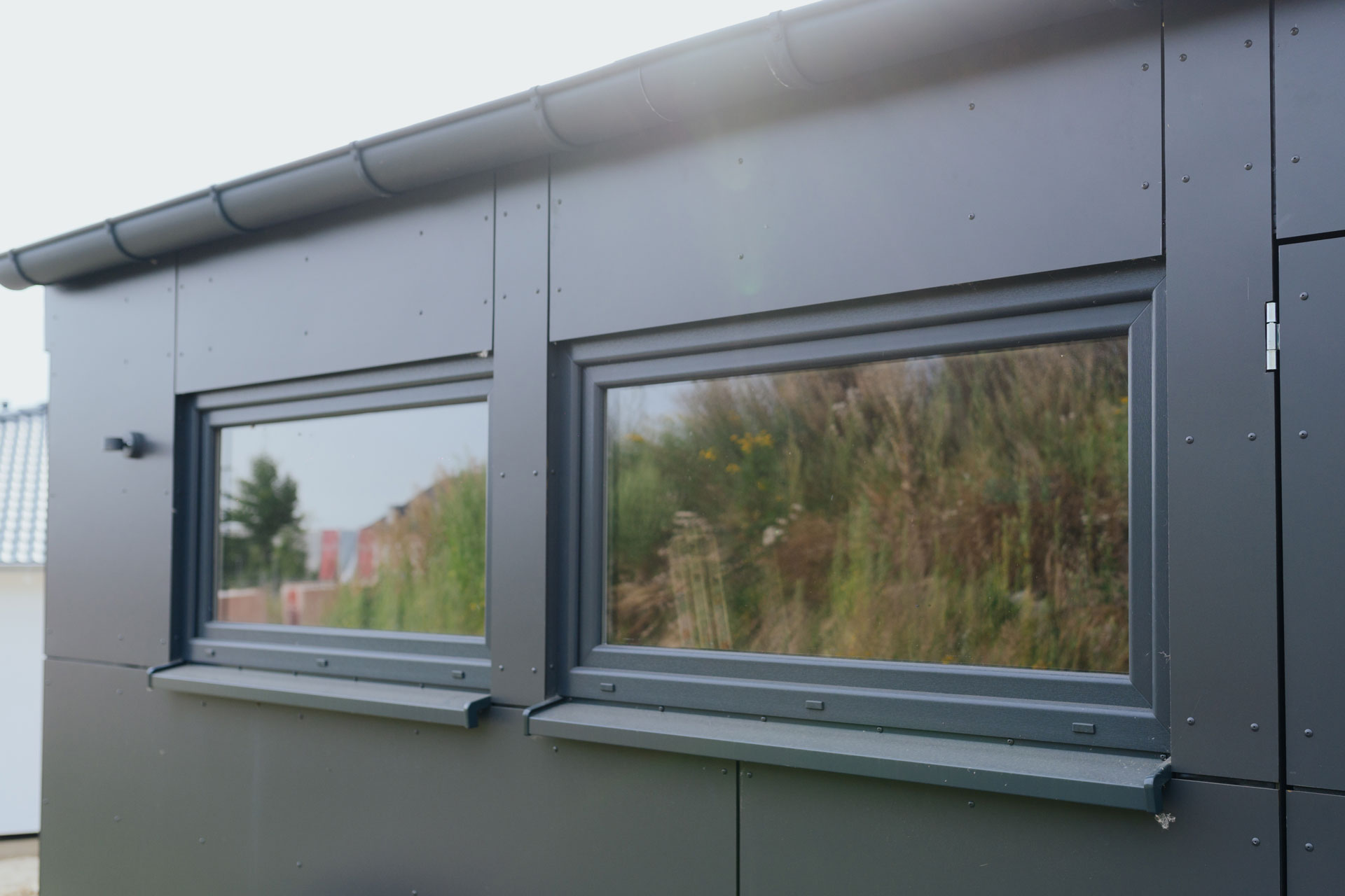 Zwei seitliche Fenster sind umgeben von schiefergrauer Außenverkleidung.
