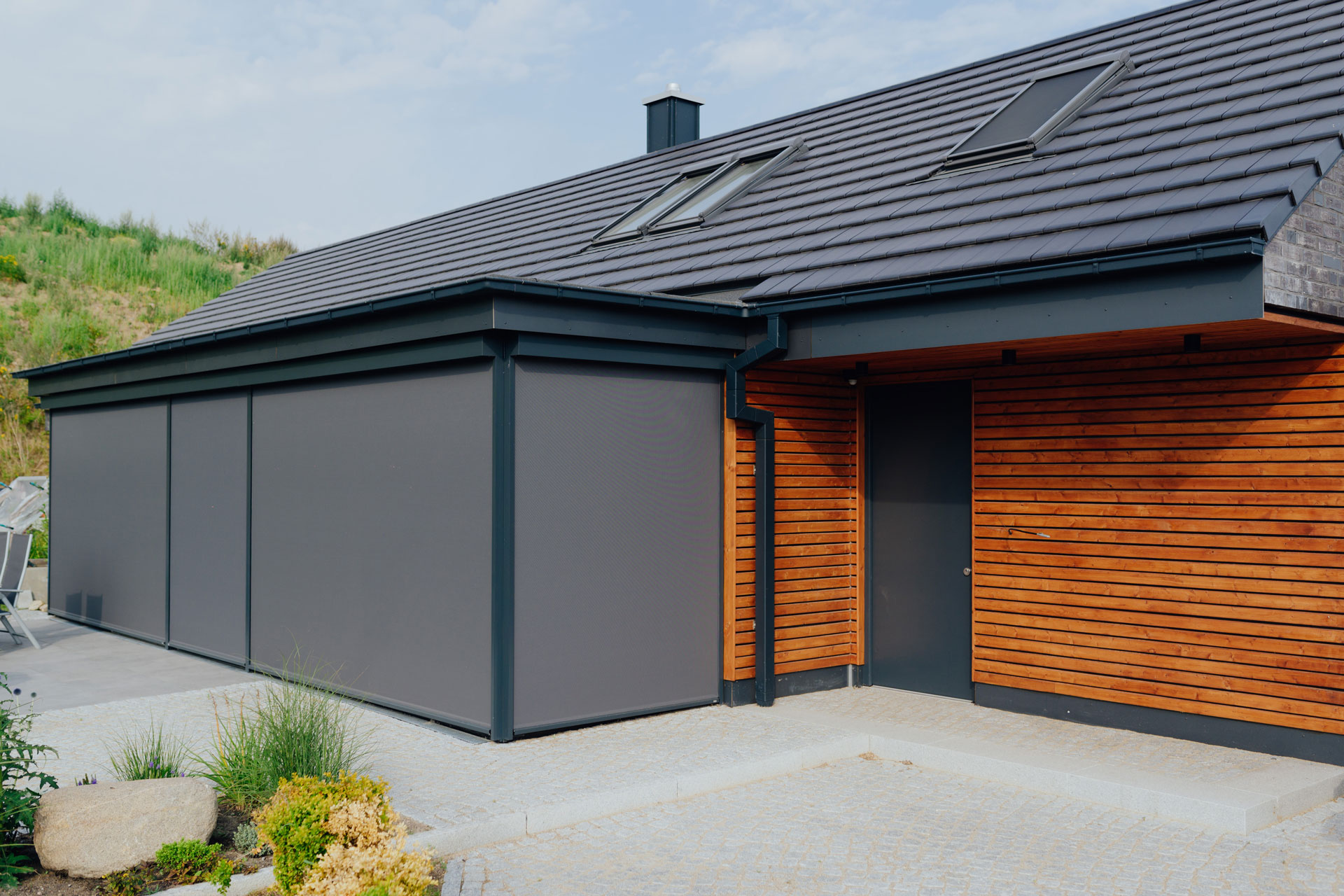 Der seitlich angebaute Carport fügt sich farblich und in seinen Materialien ans Haus ein.
