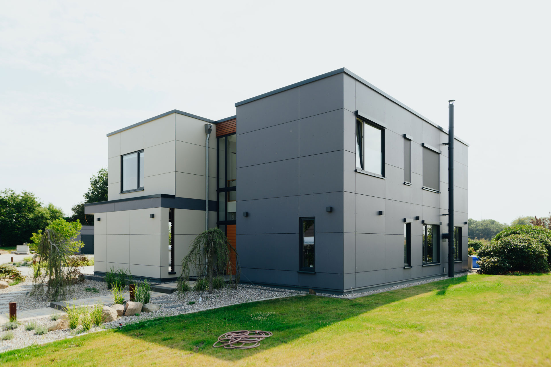 Seitlich neben dem geometrisch und klar wirkenden Haus ist eine gepflegte Rasenfläche.