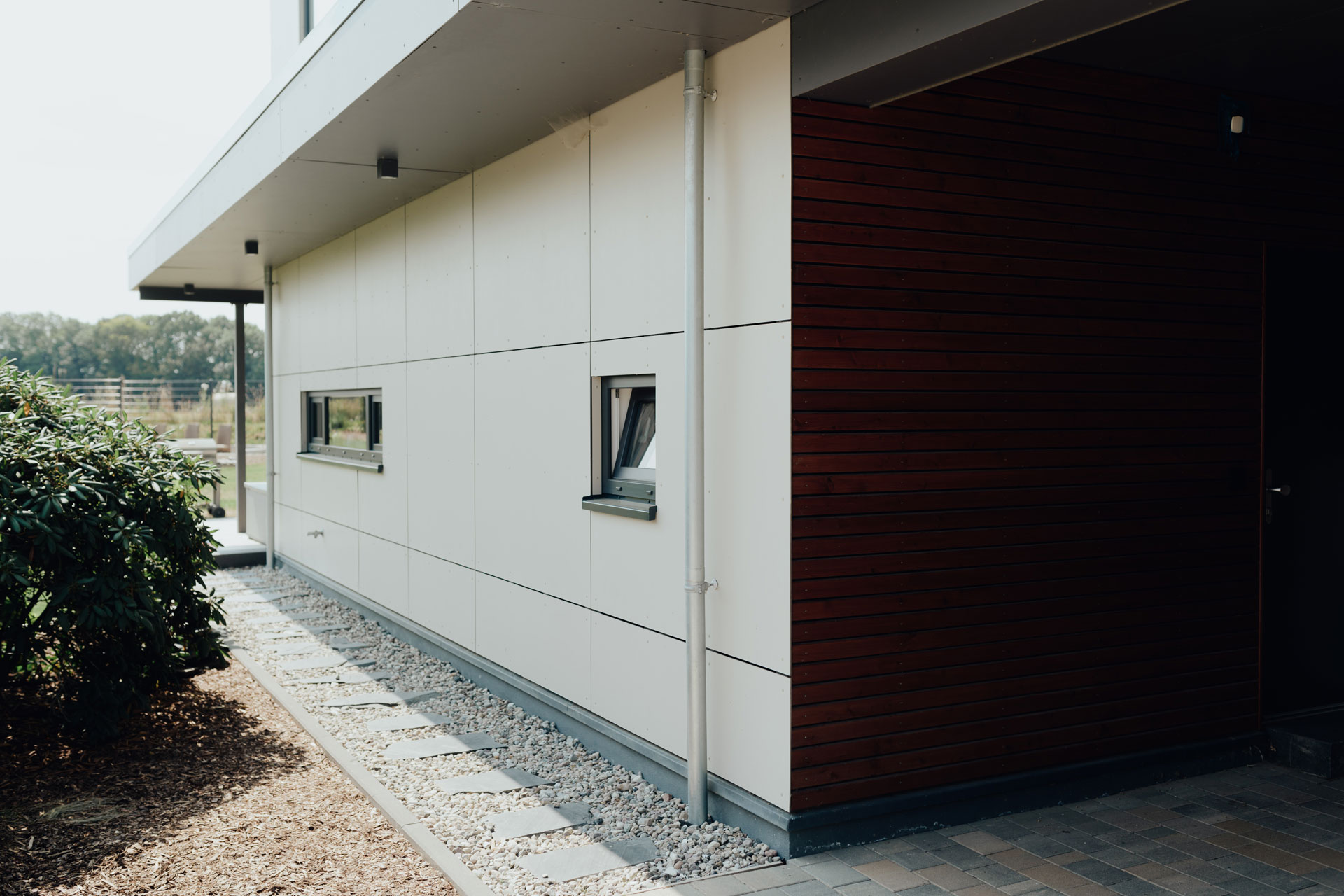 Die Seitenwand des Hauses ist weiß verkleidet.
