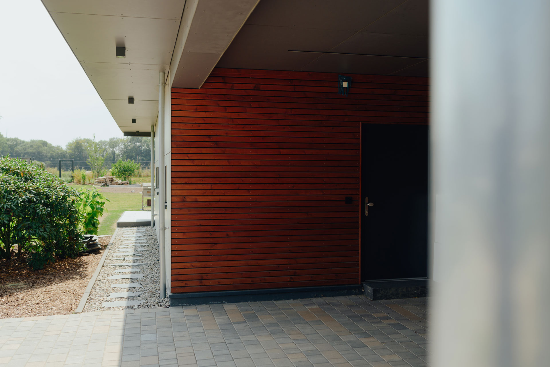 Die Seitenwand des Carports, die ans Haus angrenzt ist mit Holz verkleidet.