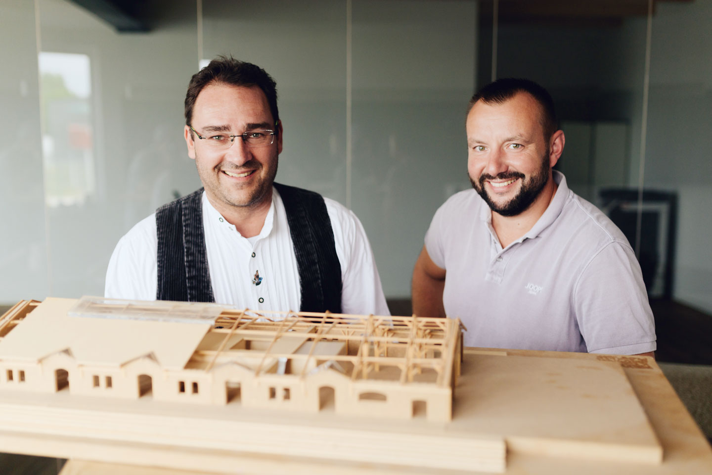 Marco Krenz und Stefan schauen über ein Holzmodel. Sie lächeln beide.