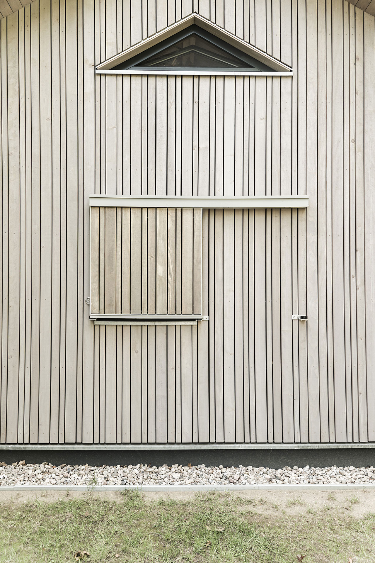 Eine Seitenwand aus Holz hat ein dreieckiges Fenster im oberen Bereich.
