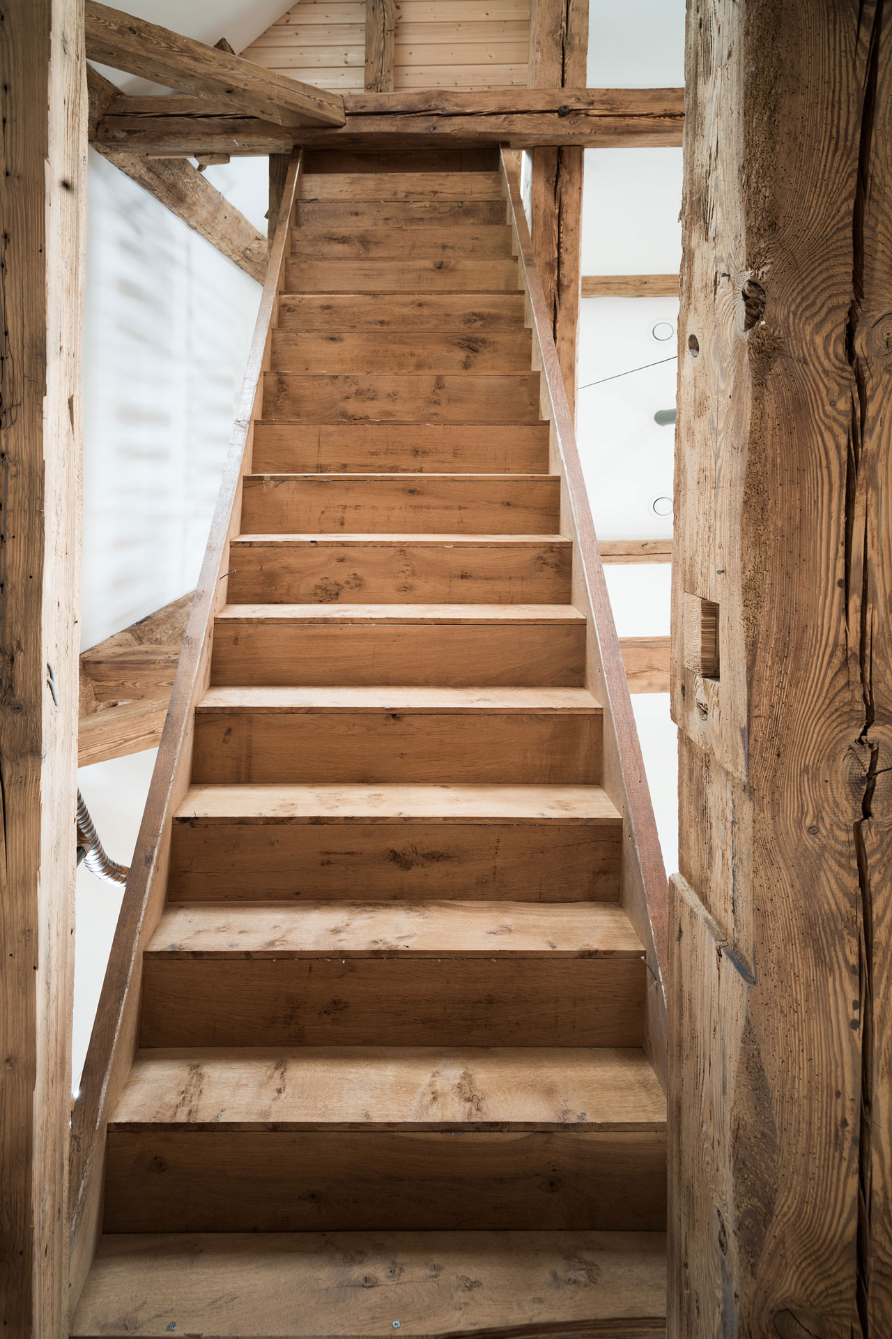 Eine helle Holztreppe führt nach oben.