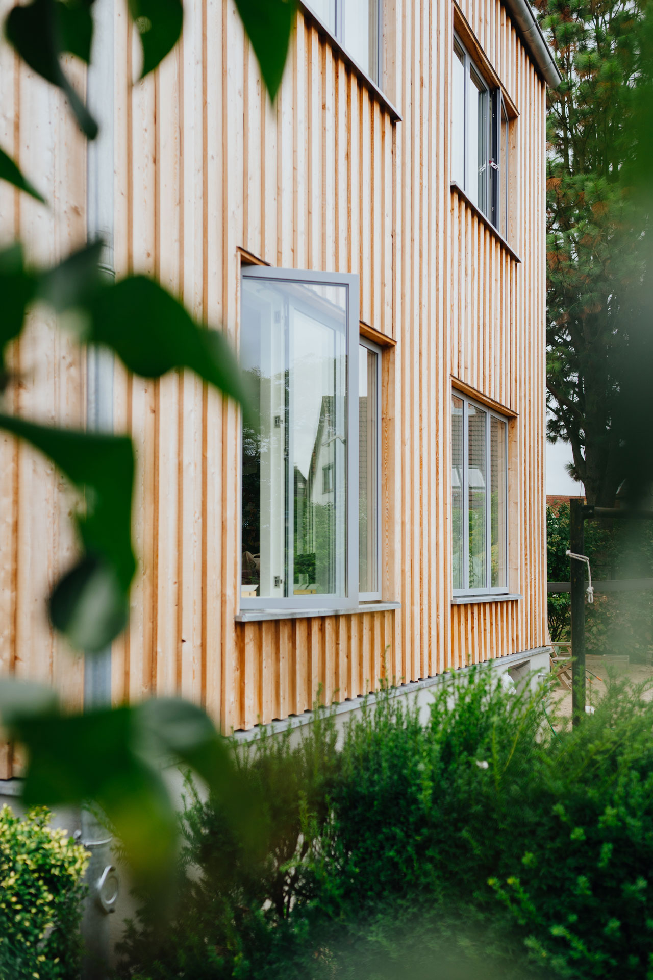 Ein Fenster im Erdgeschoß des Holzanbaus ist geöffnet.