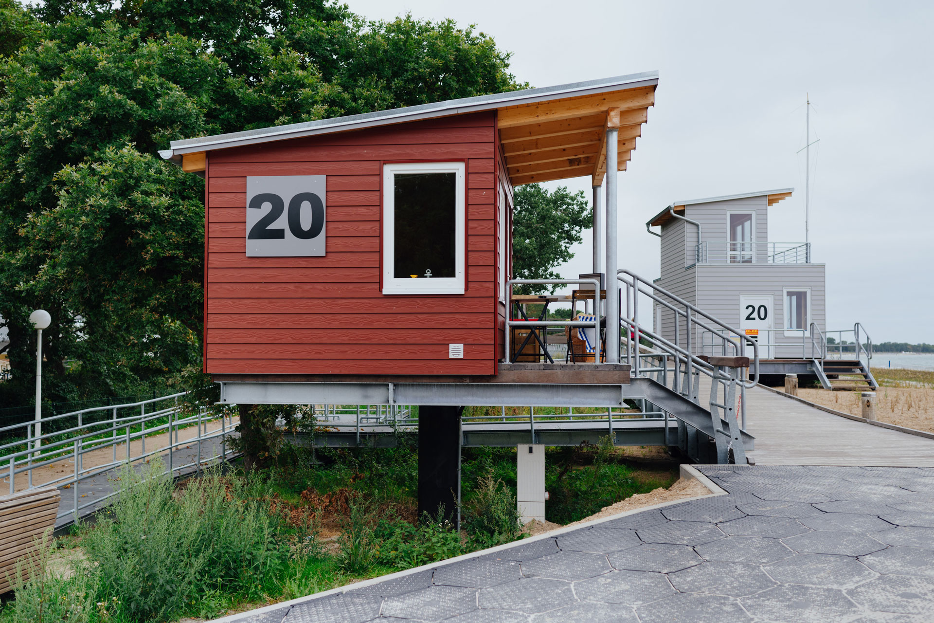 An einem Strandhaus mit braunrot gestrichenen Holz steht die Nummer 20 auf einem Schild.