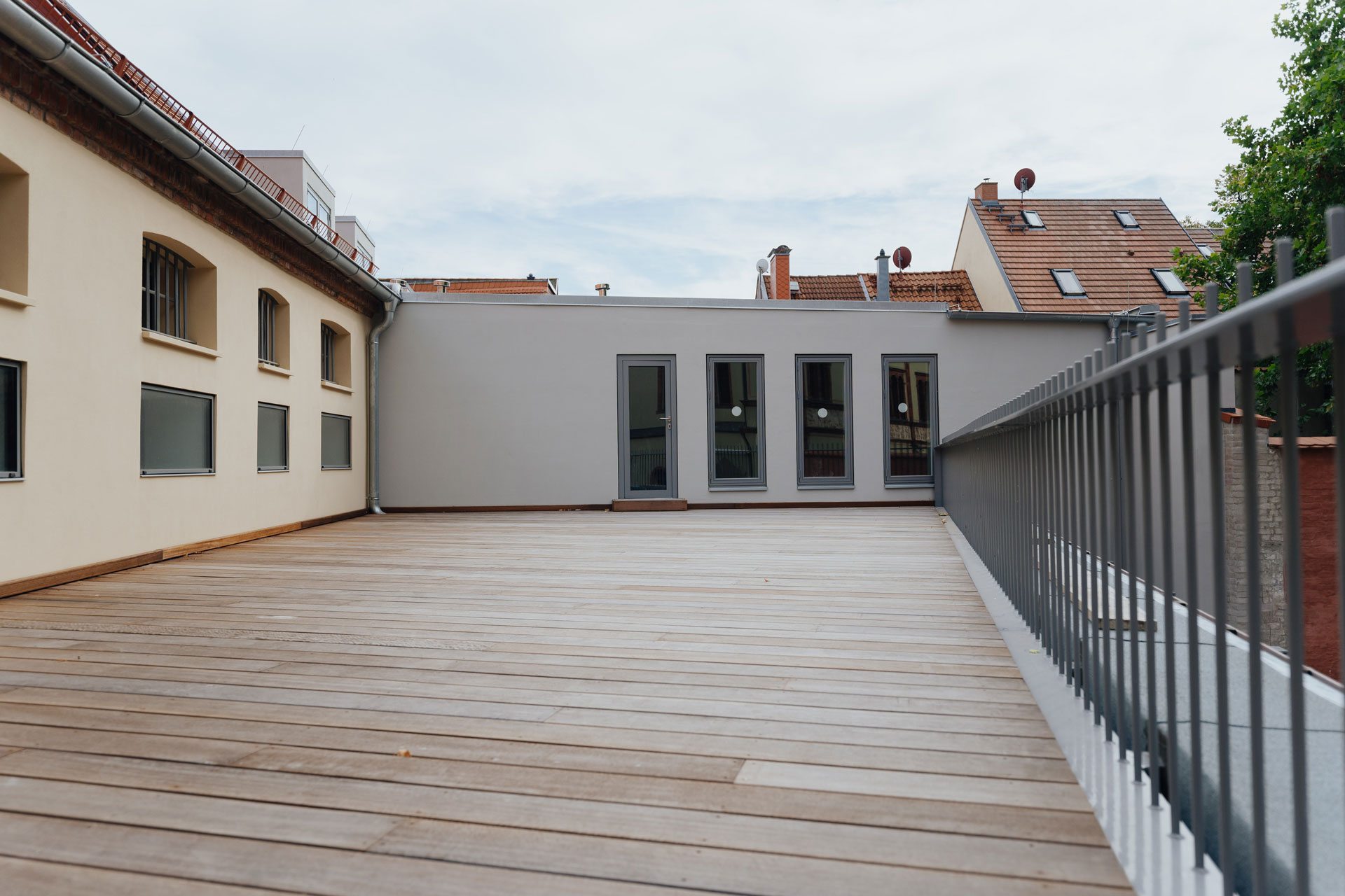 Am Ende einer großen Holzterrasse ist eine Fassade mit vier länglichen Fenstern.
