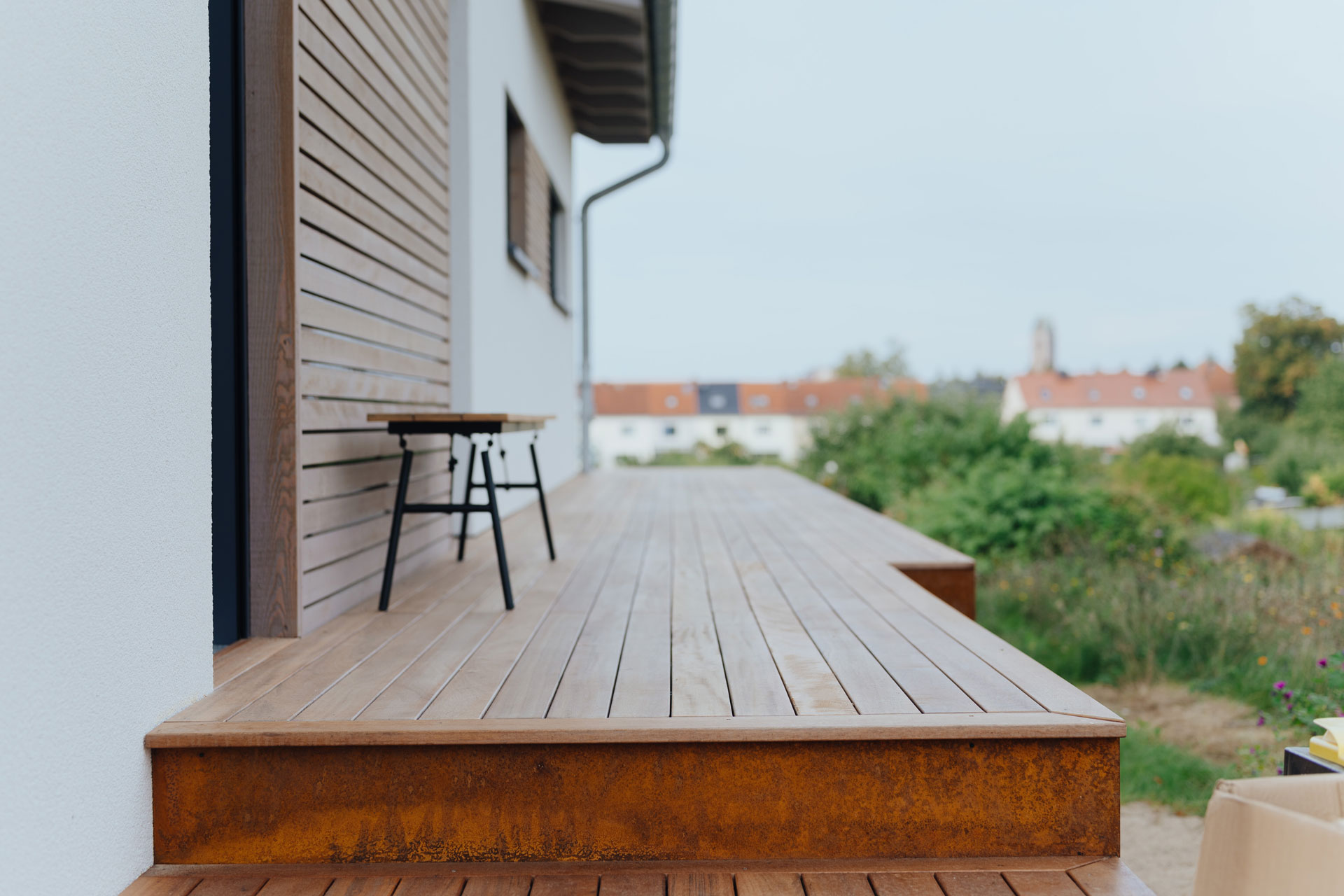 Terrassenstufen führen zu einer Terrasse. Beide ist mit Holz verkleidet.