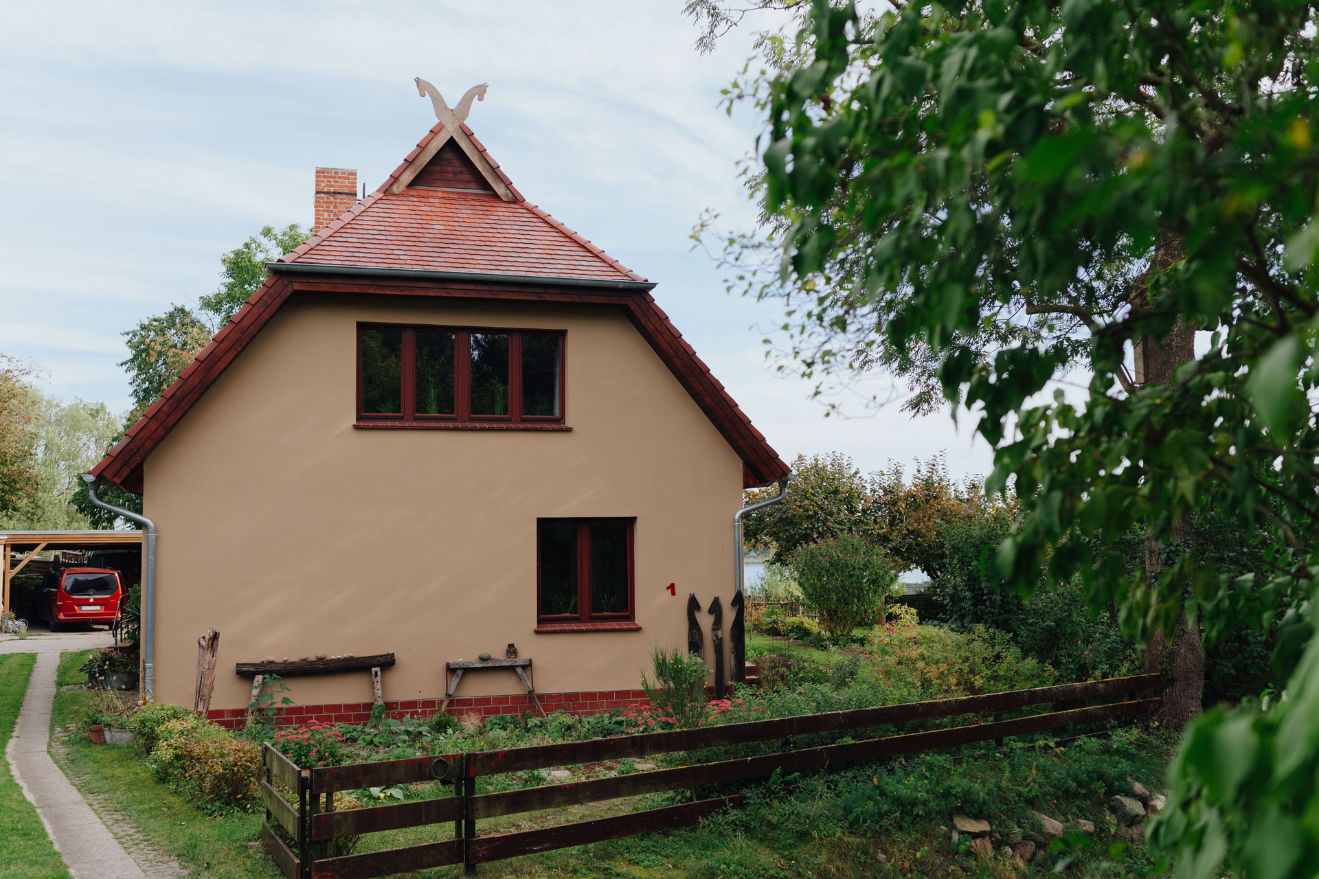 Ein großer Baum steht auf der Rückseite des Einfamilienhauses. Es ist Sommer.