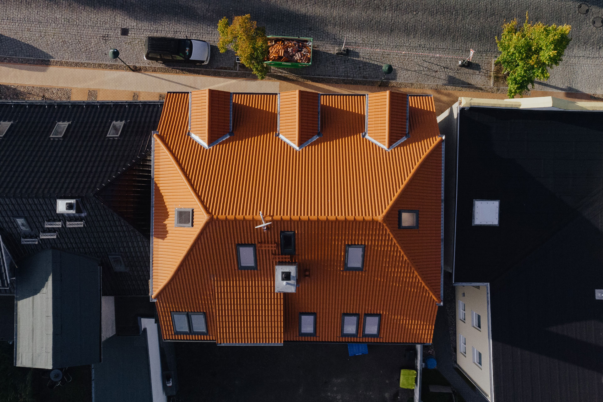 Das rote Ziegeldach eines Mehrfamilienhauses ist direkt darüber aus der Vogelperspektive aufgenommen.