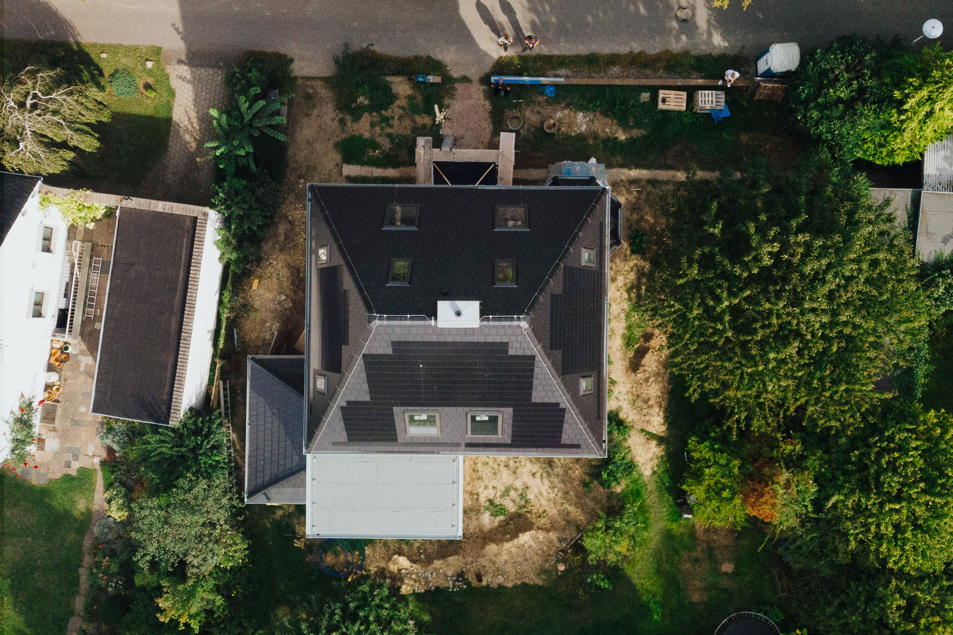 Auf einem freistehenden Einfamilienhaus sind schwarze Solardachziegel auf drei Seiten des Daches.