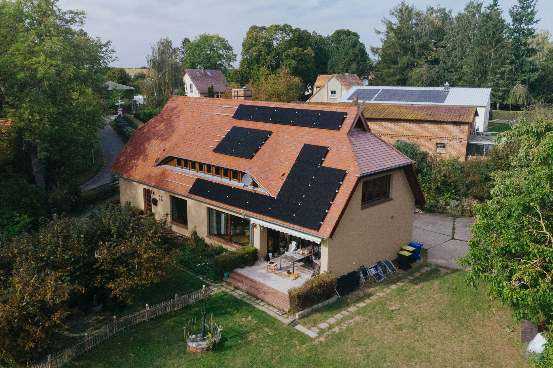 Ein großer Rasenbereich ist vor einem Einfamilienhaus. Auf dem Dach ist eine Solaranlage.