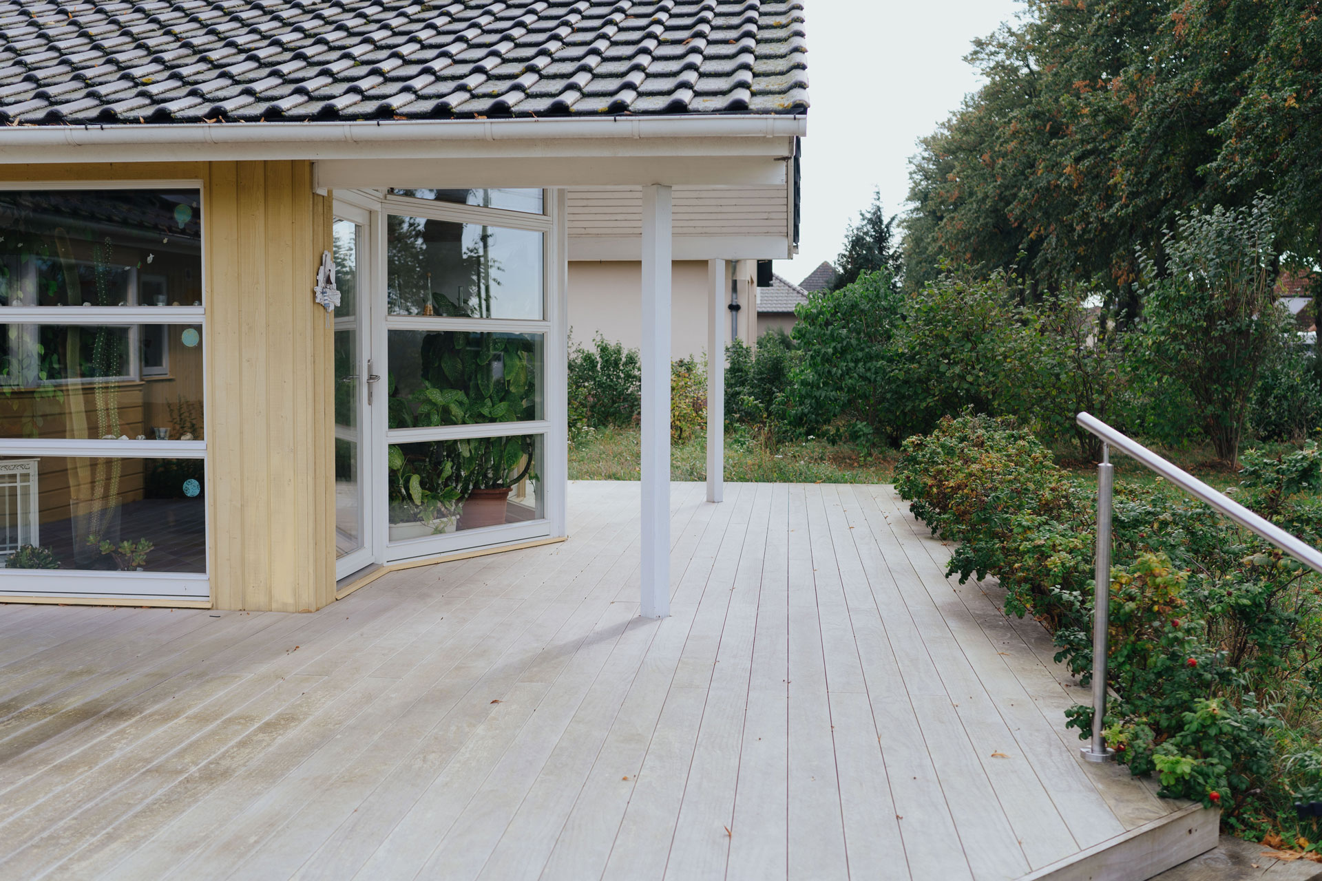 Stufen mit Geländer führen zu einer Terrasse mit Holzboden.