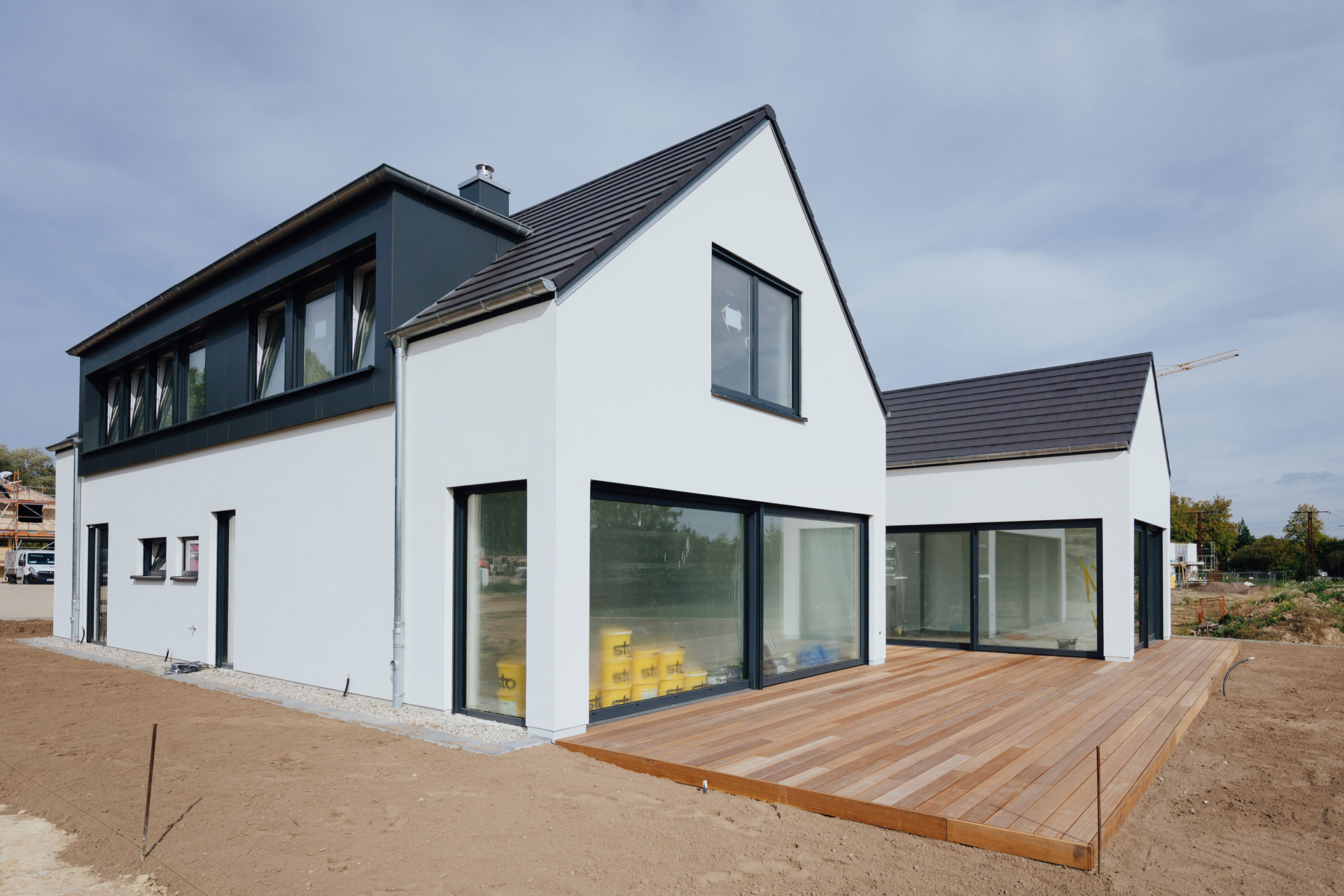 Ein Einfamilienhaus hat einen großzügige Holzterrasse. Das Haus ist noch nicht bezogen.